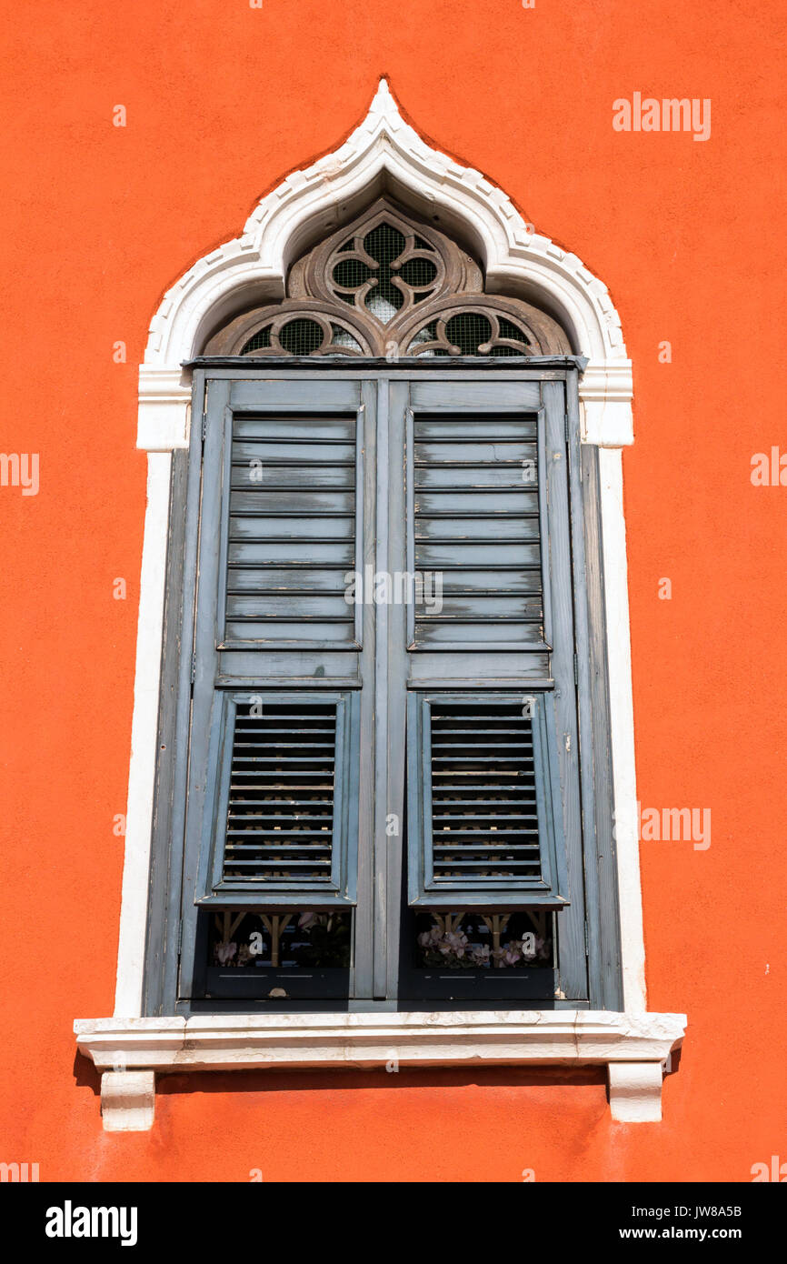 Vintage design fenêtre avec volets sur un mur orange. Banque D'Images