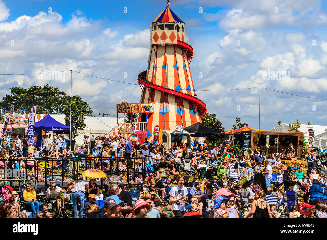 Rassemblement près de la foule des stands de nourriture et de divertissement, avec un traditionnel helter skelter spiral slide, Jimmy's Festival, Ipswich, Suffolk, UK Banque D'Images