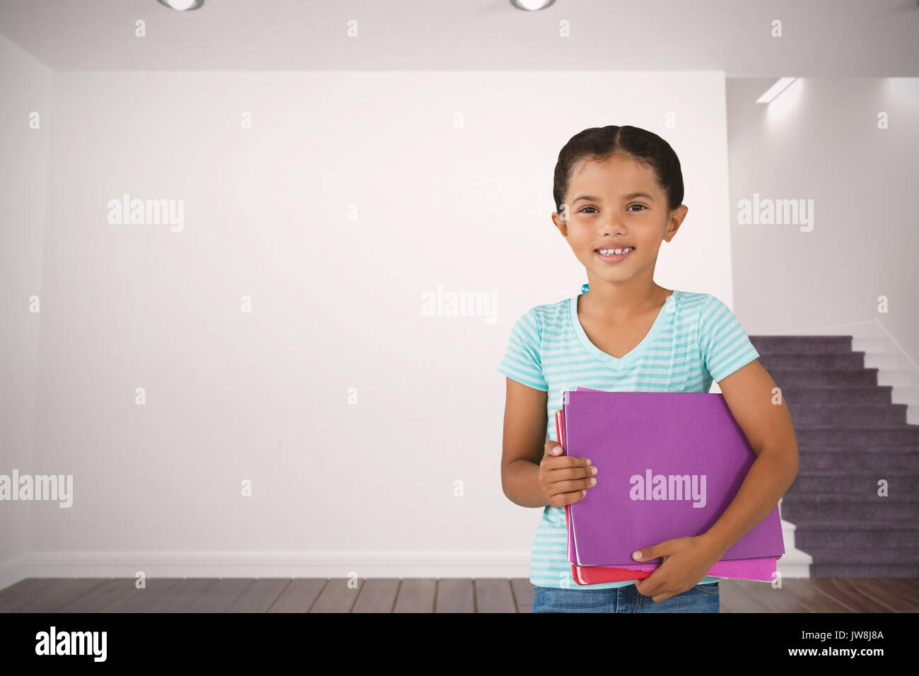 Portrait of smiling girl holding files contre chambre blanche avec escaliers Banque D'Images