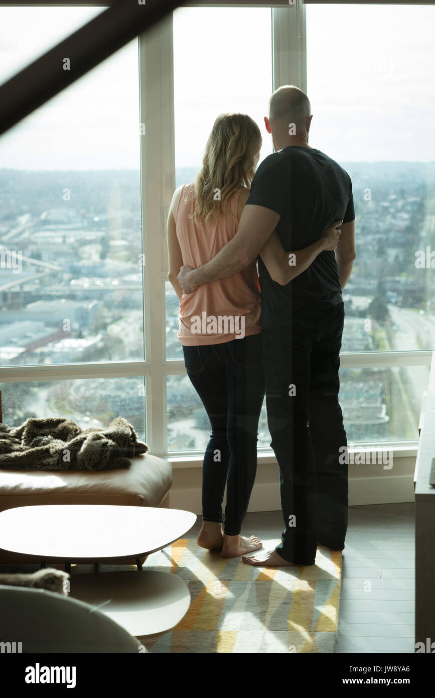Vue arrière du couple hugging les uns les autres dans la salle de séjour à la maison Banque D'Images