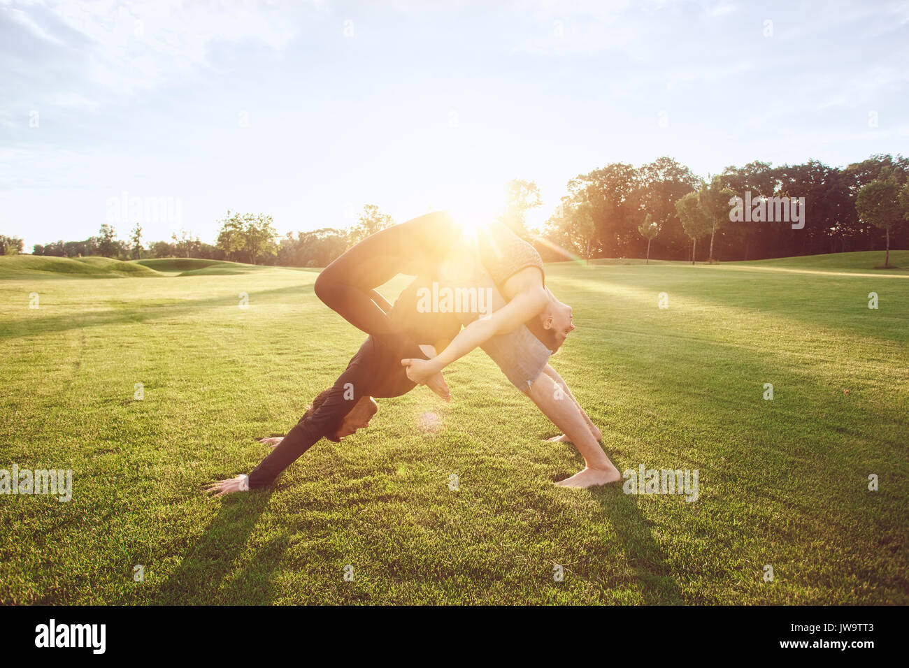 L'homme et de la femme pratique le yoga dans le parc acro Banque D'Images