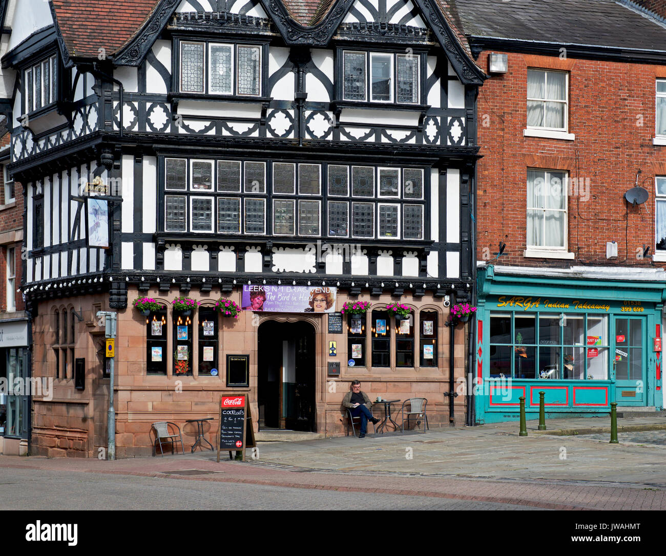 Homme assis à l'extérieur de l'oiseau dans la main, un pub à Leek Marstons, Staffordshire, Angleterre, Royaume-Uni Banque D'Images