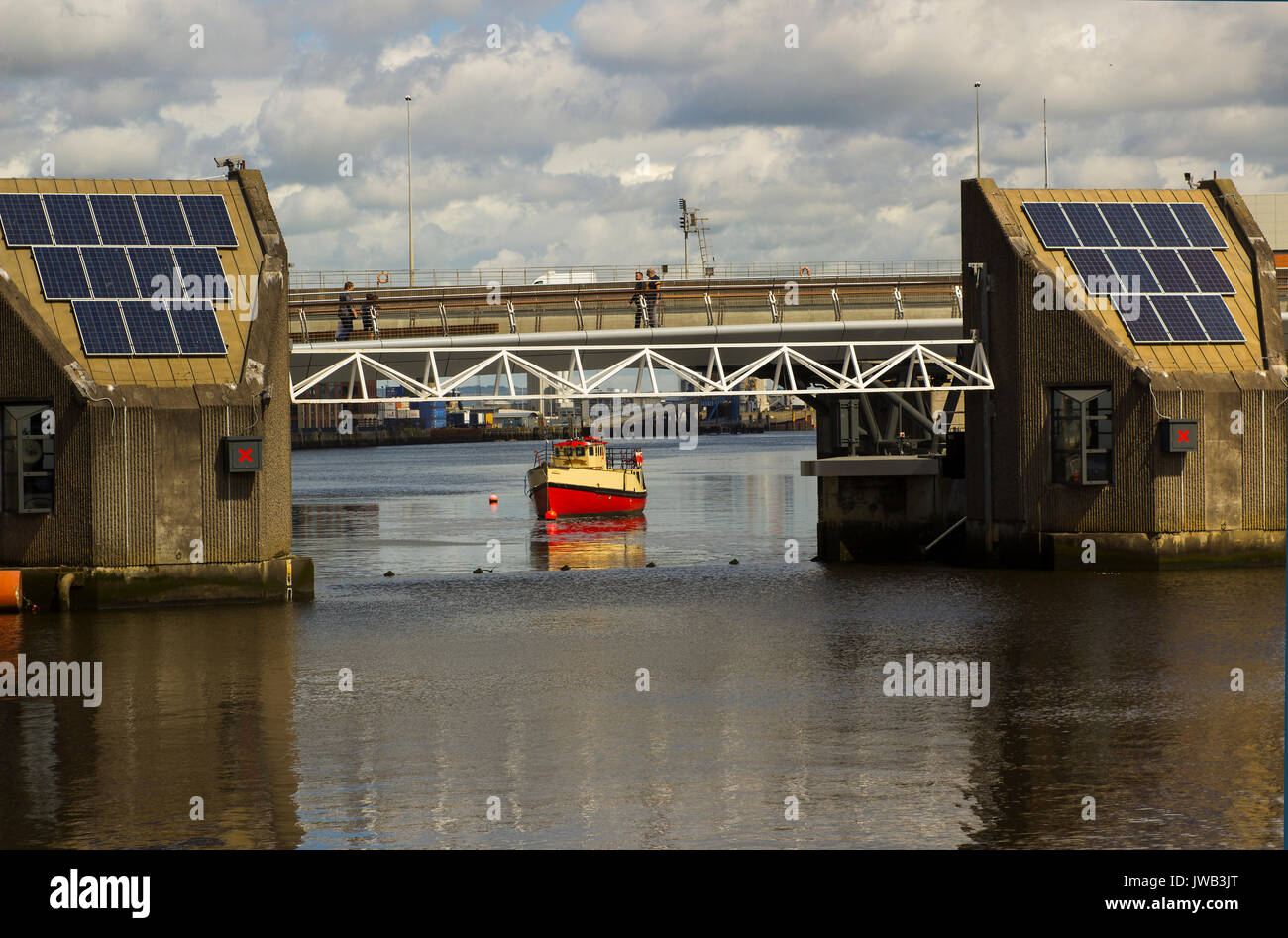 Les piétons traverser la rivière Lagan sur la passerelle de l'autre côté de la barrière de défense contre les inondations dans la région de Belfast, Irlande du Nord Banque D'Images