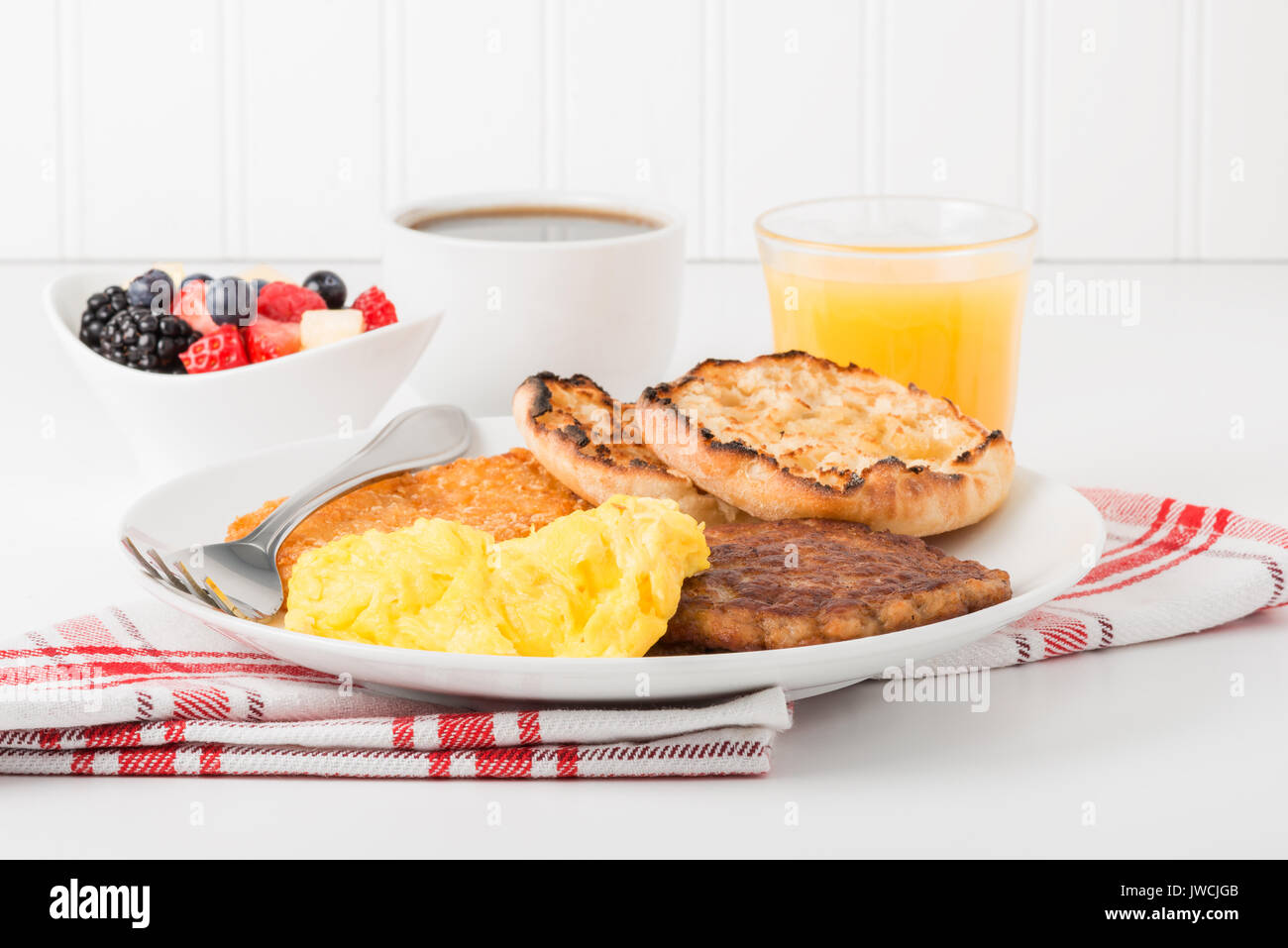 Petit déjeuner d'œufs brouillés, saucisses, fruits et café. Banque D'Images