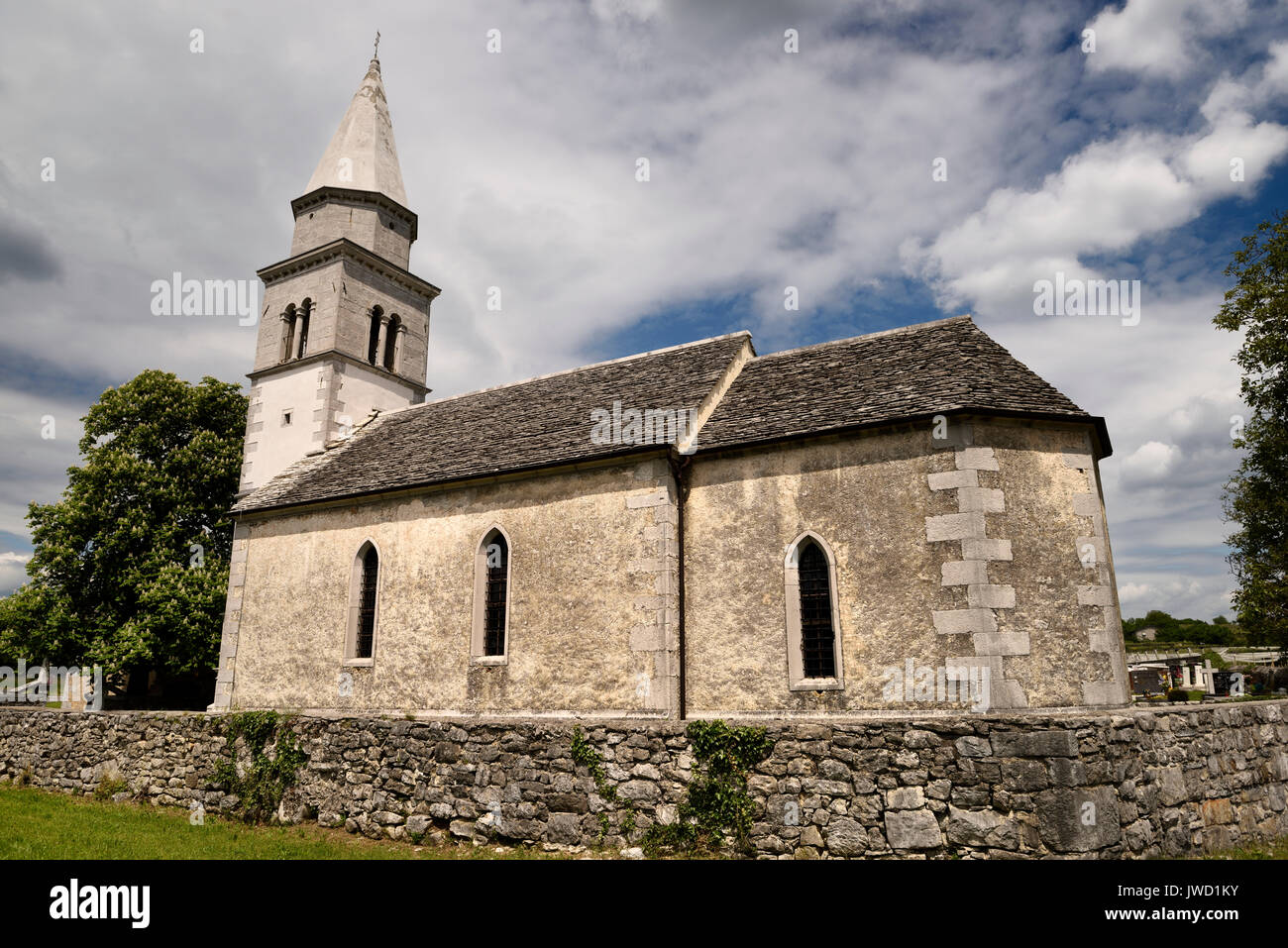 Toit de tuiles en pierre de l'église de la Sainte Croix à côté d'un cimetière de Kriz Sezana Slovénie avec marronnier Banque D'Images