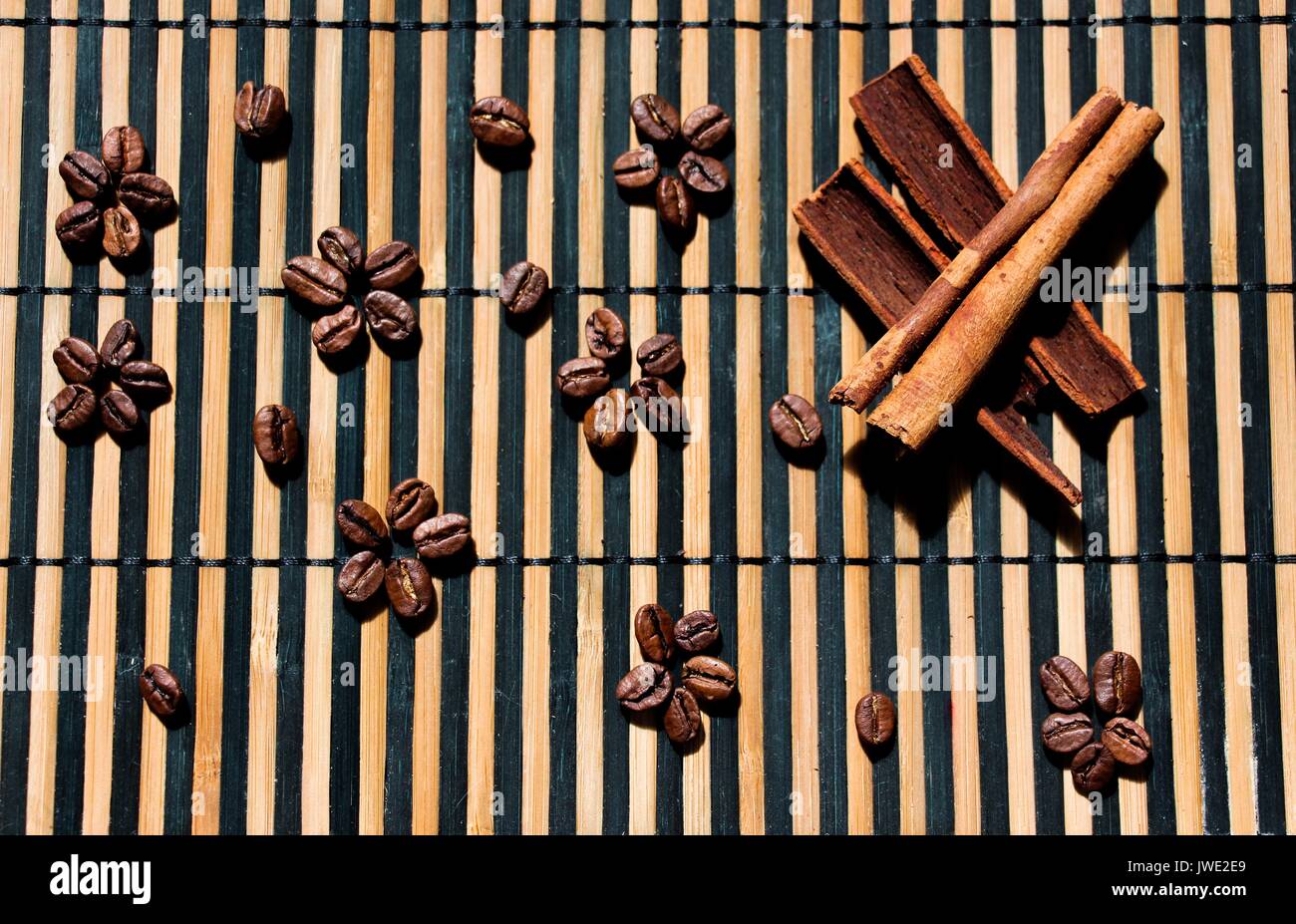 Des grains de café frais sont disposés sur la surface en bois avec de magnifiques et beaux modèles. Près de la cannelle est mis à baguettes. Les produits sont fr Banque D'Images