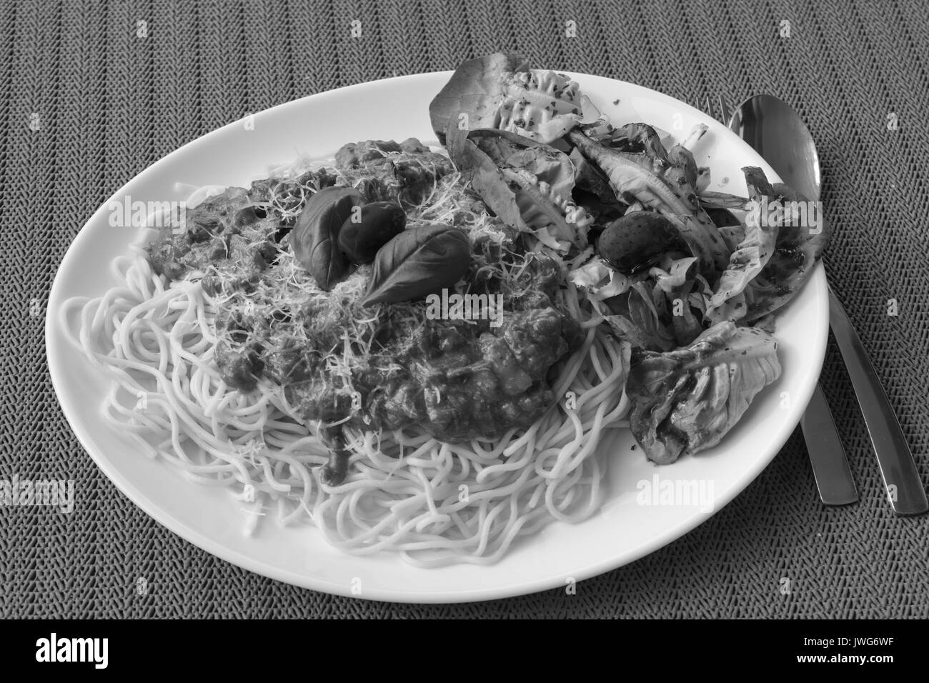 Spaghettis à la bolognaise au basilic, salade verte et rouge olives espagnoles. Image en noir et blanc. Banque D'Images