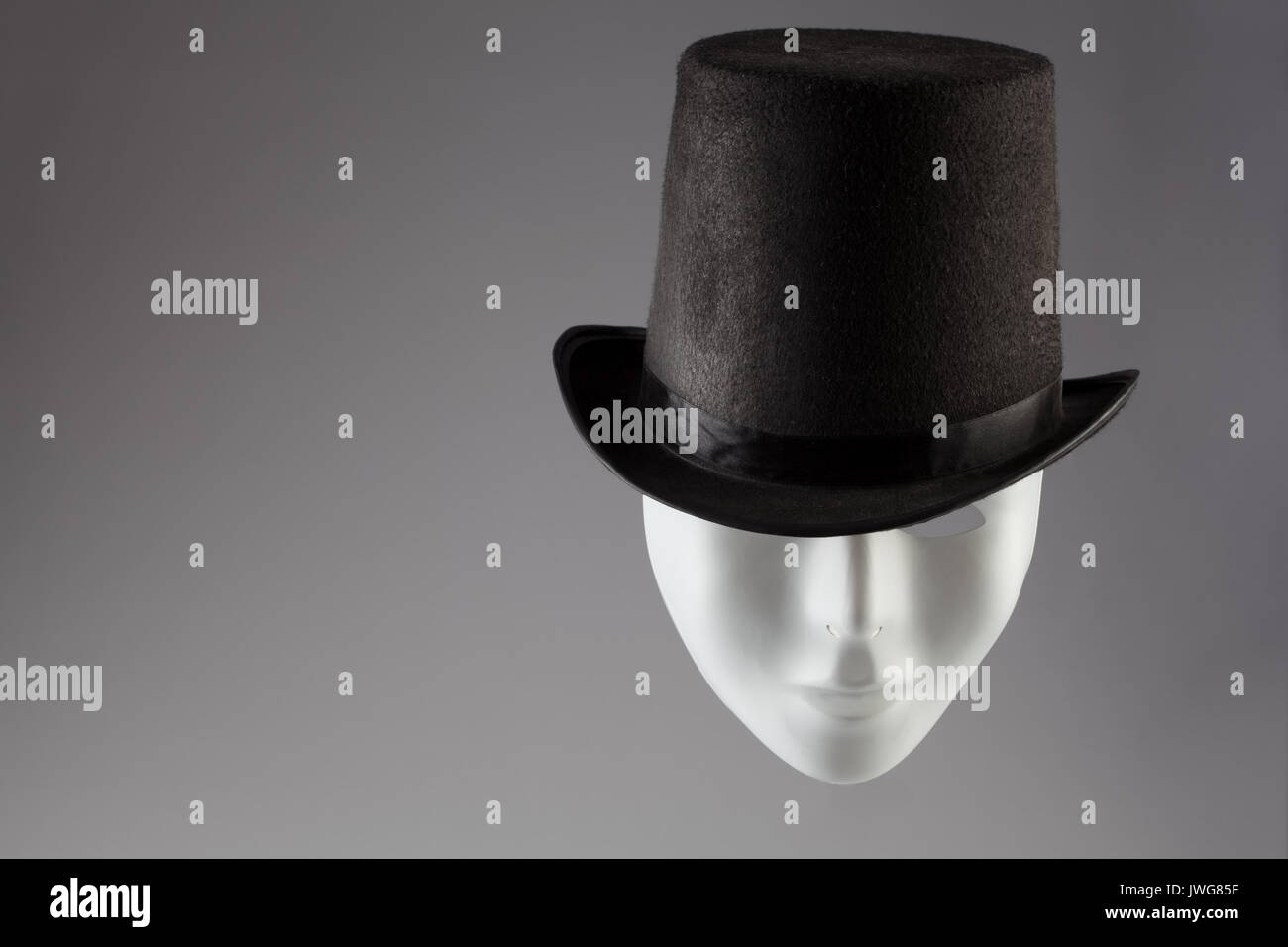 Masque blanc vêtu de noir sur fond gris top hat with copy space Banque D'Images
