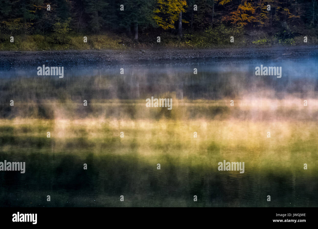 La surface de la forêt brumeuse lake au lever du soleil. belle nature fond colorées de la fumée s'élevant au-dessus de l'eau Banque D'Images