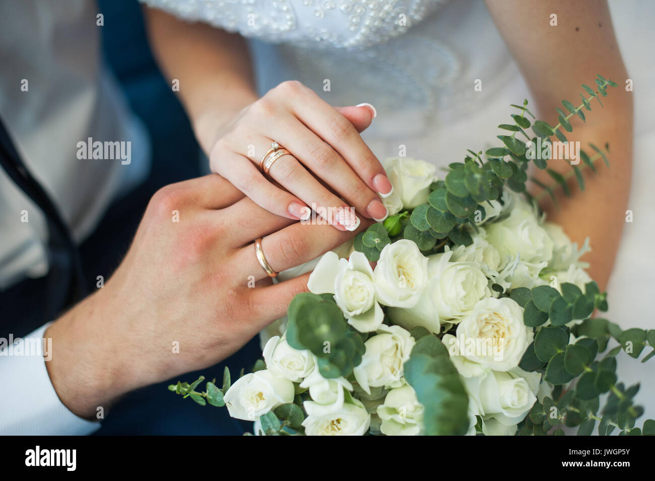Les mains des mariés avec des anneaux sur un bouquet de mariage Banque D'Images