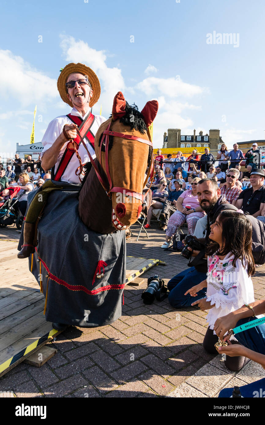 Festival de la semaine folklorique annuelle de Broadstairs. Man riding hobby horse, l'Harwich Morris bête, imbécile, en face de l'auditoire et les enfants. Une jeune fille enfant tendant la main pour toucher la tête de cheval. Banque D'Images