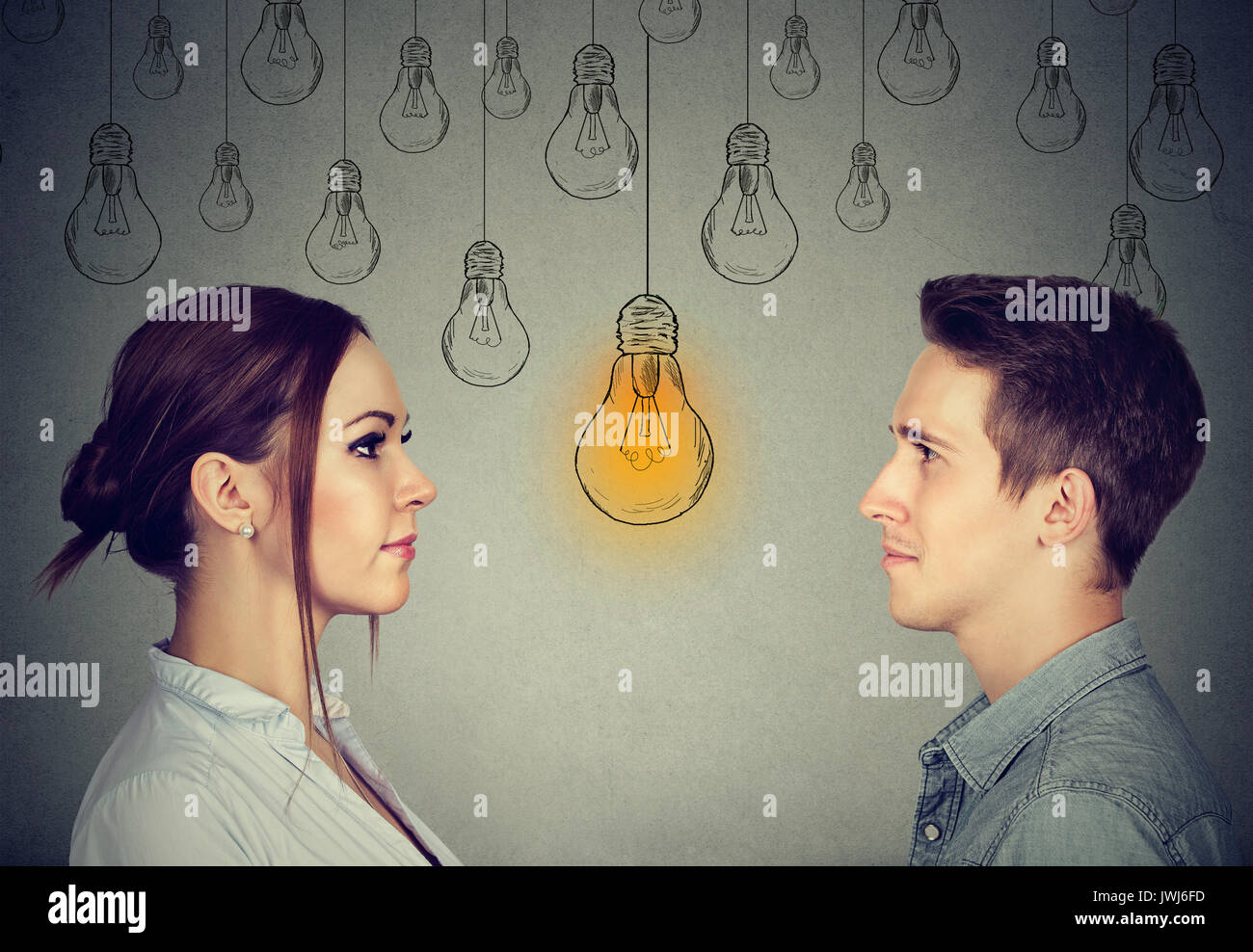 Compétences cognitives capacité concept, Homme vs femme. L'homme et la femme à la lampe à lumière vive isolé sur fond de mur gris Banque D'Images