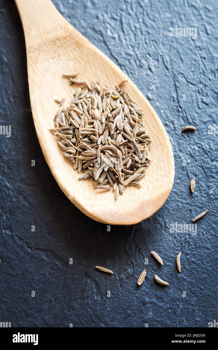 Les graines de cumin à la cuillère sur le fond de la pierre noire, Close up Banque D'Images