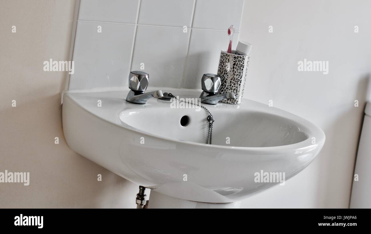 Petit lavabo blanc en anglais toilettes avec deux robinets près de brosse à  dents Photo Stock - Alamy