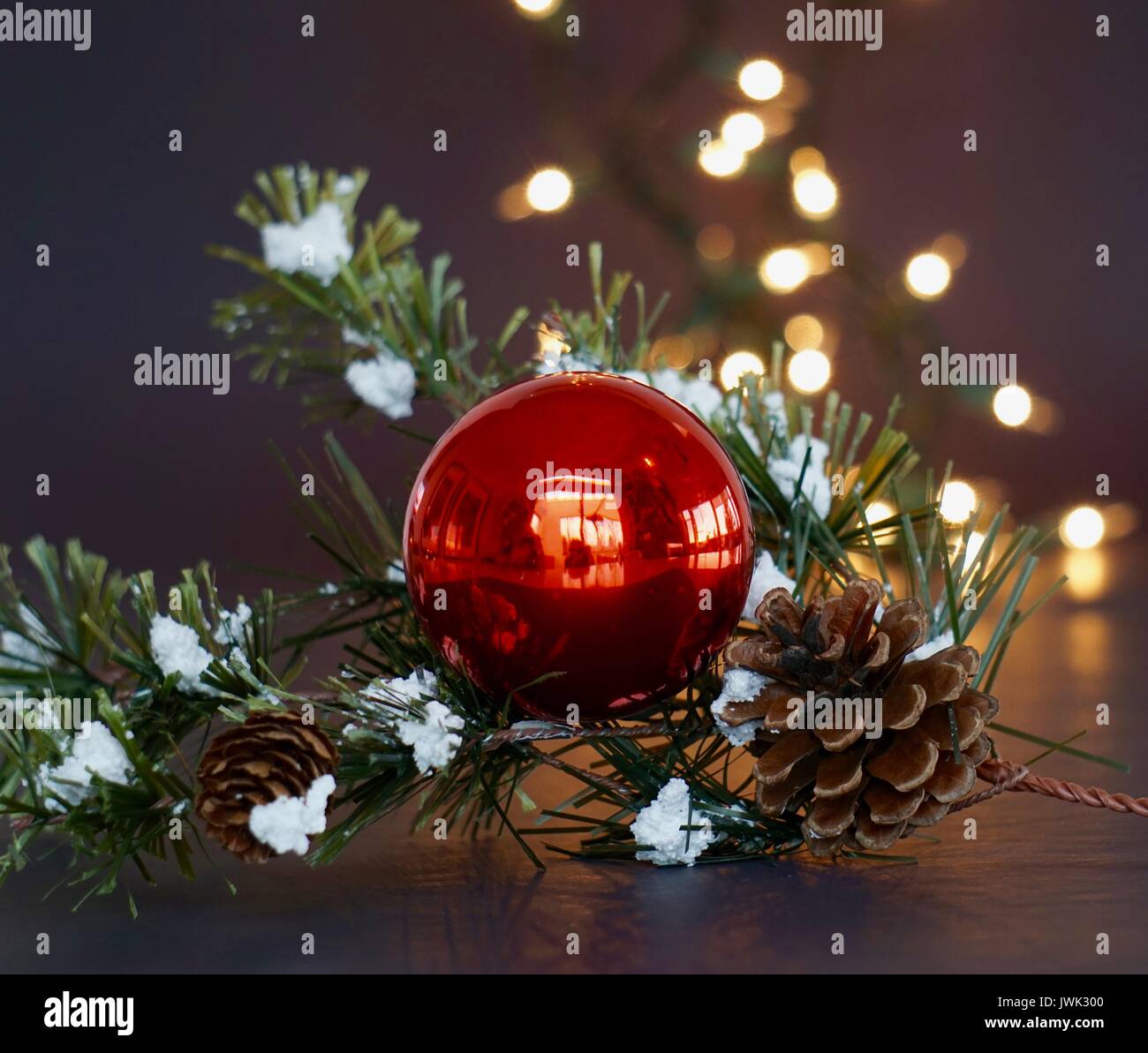 Boule de Noël rouge avec des lumières blanches et garland boisé Banque D'Images