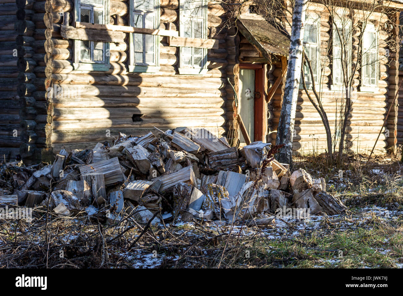 Des troncs d'arbres sciés pour fendre le bois de chauffage. Dans l'arrière-plan est une vieille maison en bois. Banque D'Images
