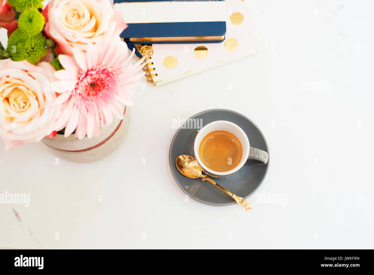 Concept de poste de travail féminin dans télévision jeter style avec du café, des fleurs, des blocs-notes sur fond de marbre blanc. Vue de dessus, clair, rose et or Banque D'Images