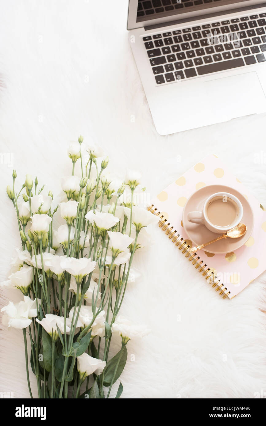 Ordinateur portable, ordinateur portable, café et un gros bouquet de fleurs blanches sur le sol sur un tapis de fourrure blanche. Offres de la féminité de l'espace d'accueil confortable de la mode Banque D'Images