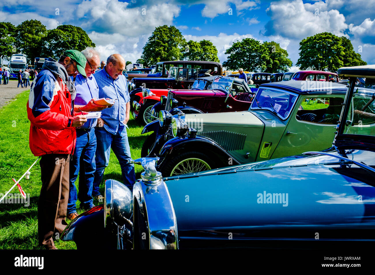 Biggar, South Lanarkshire - 44e rallye de véhicules anciens. Trois hommes admirer les voitures classiques. Banque D'Images