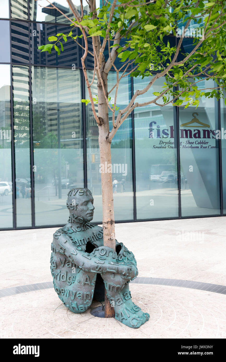 Une belle sculpture en bronze d'un homme serrant un arbre vivant à l'extérieur de l'avant la construction de gratte-ciel dans le centre-ville de Calgary Alberta Canada Banque D'Images