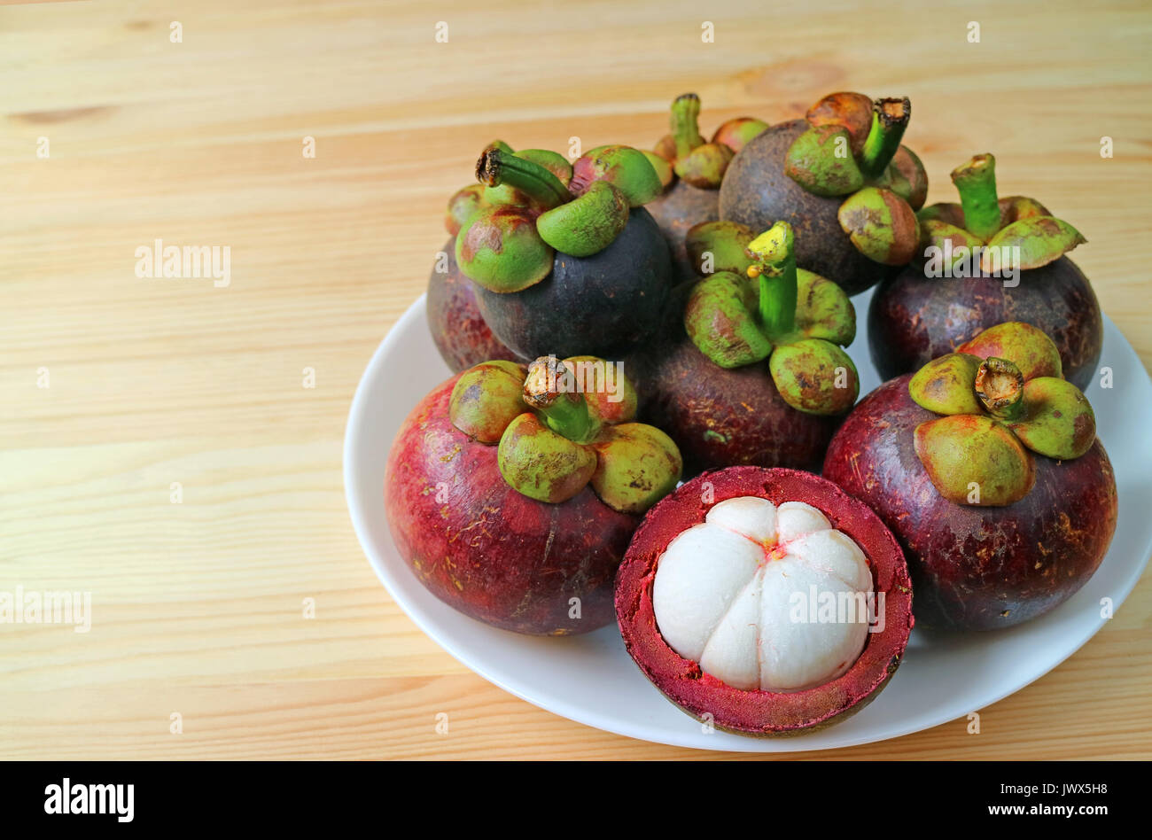 Assiette de fruits mûrs mangoustan pourpre et ouvert pour afficher la viande blanche pure délicieux sur la table en bois, avec de l'espace libre pour le texte et la conception Banque D'Images