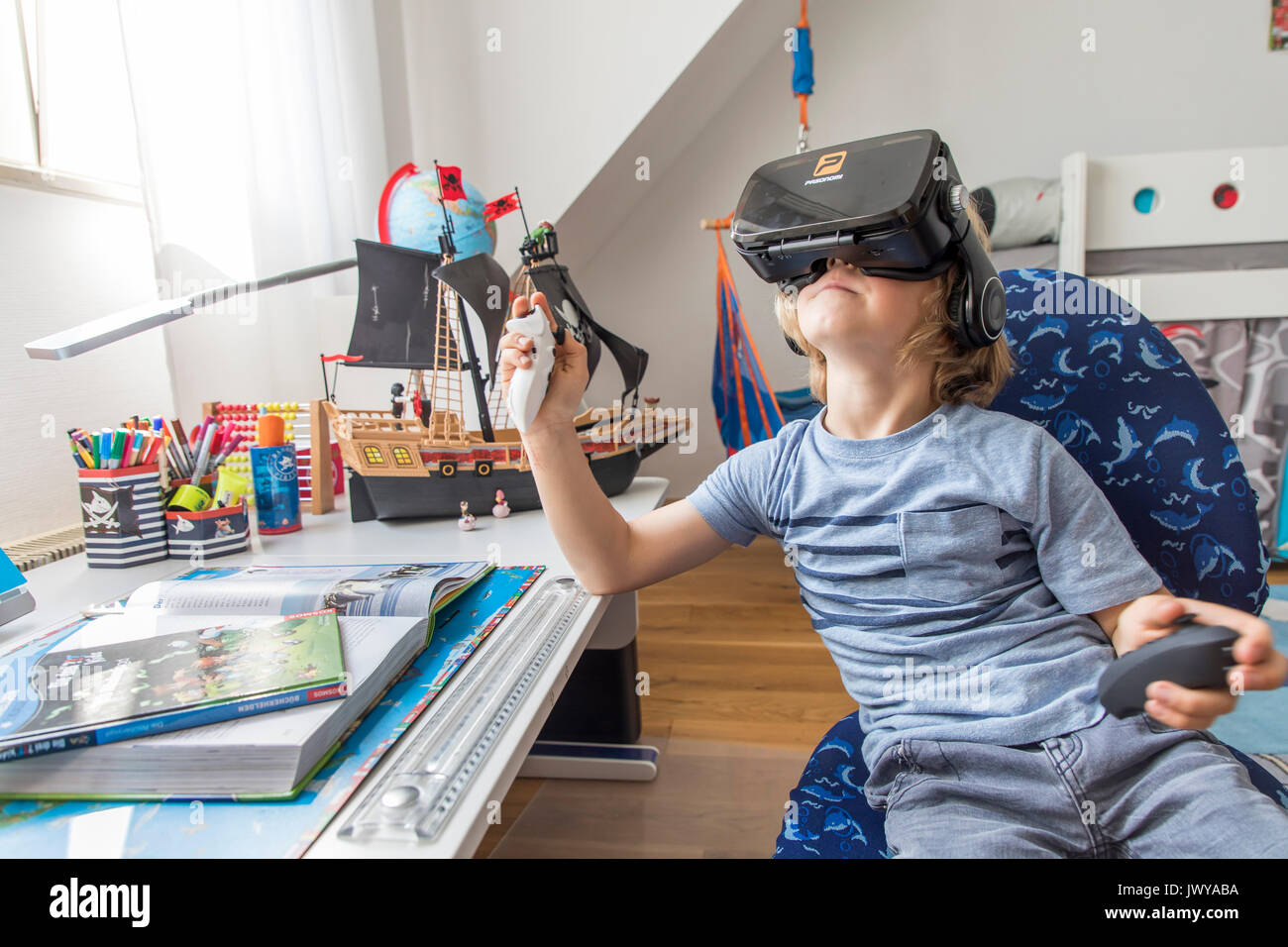 Petit garçon, 7 ans, joue un jeu d'ordinateur 3-D, avec un casque de réalité virtuelle, dans sa chambre d'enfants, Banque D'Images