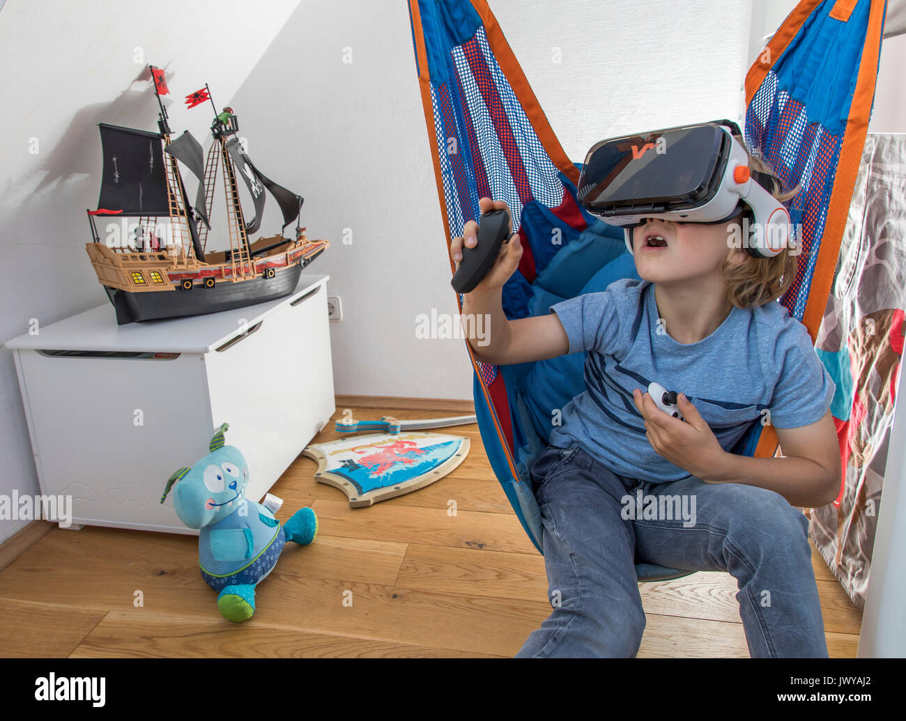 Petit garçon, 7 ans, joue un jeu d'ordinateur 3-D, avec un casque de réalité virtuelle, dans sa chambre d'enfants, Banque D'Images