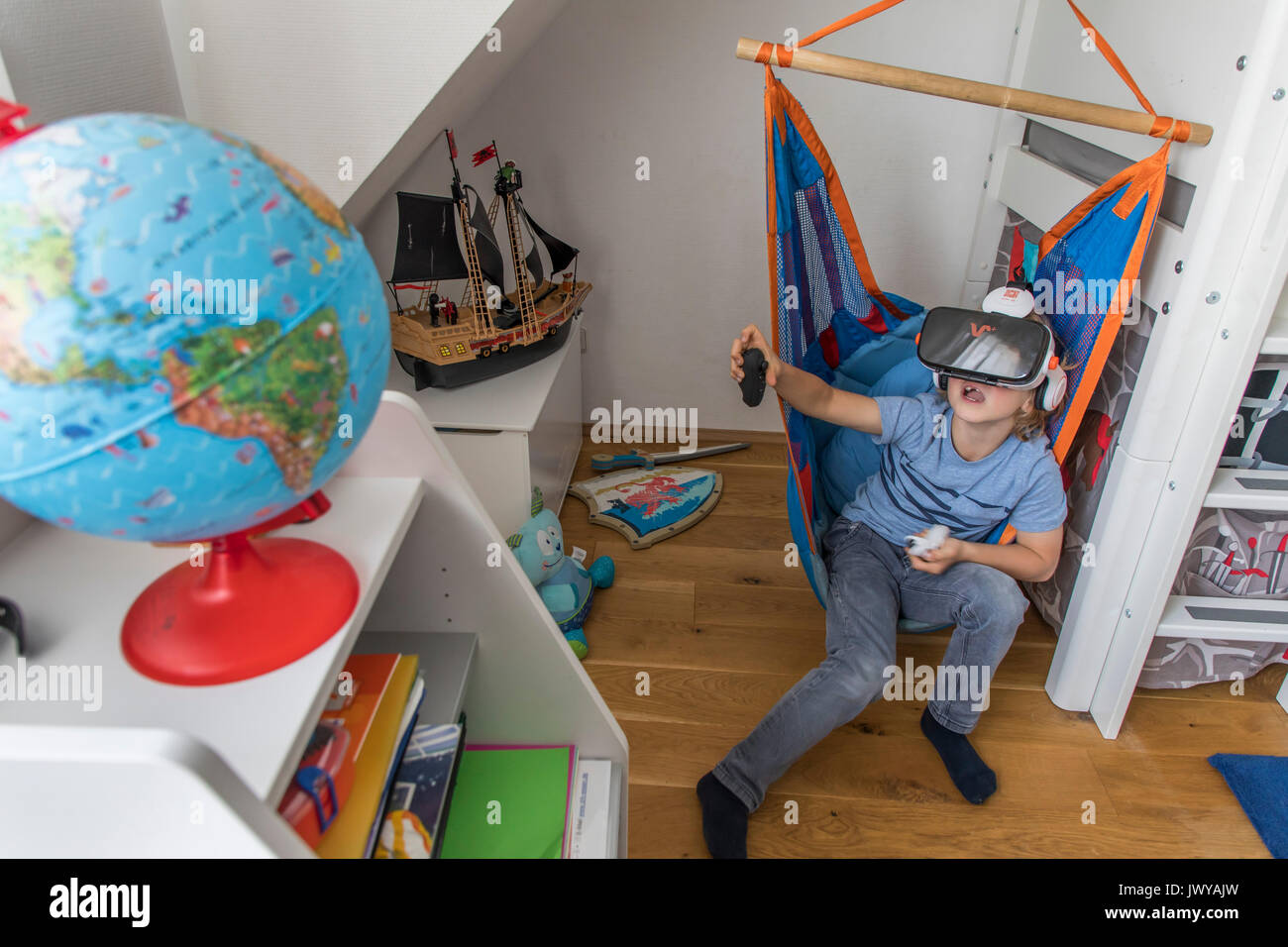 Petit garçon, 7 ans, joue un jeu d'ordinateur 3-D, avec un casque de réalité virtuelle, dans sa chambre d'enfants, Banque D'Images