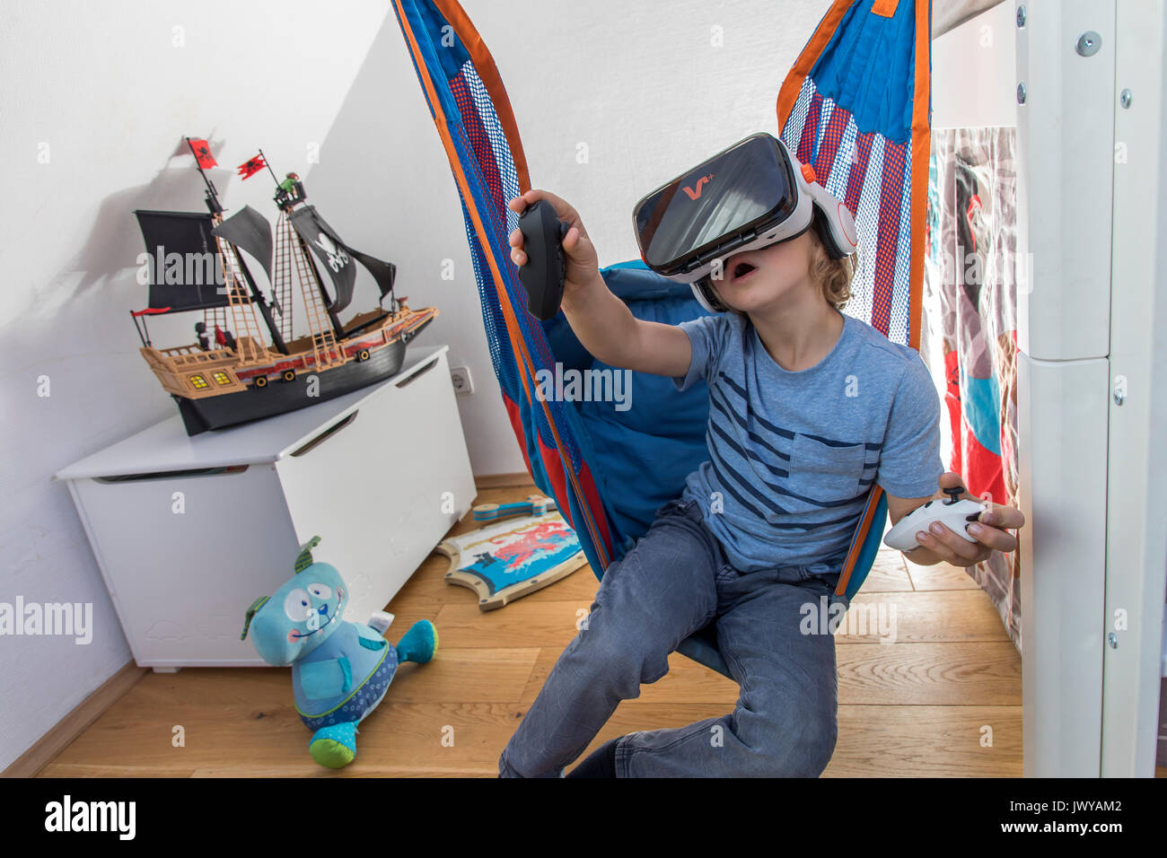 Petit garçon, 7 ans, joue un jeu d'ordinateur 3-D, avec un casque de réalité virtuelle, dans sa chambre d'enfants, Banque D'Images
