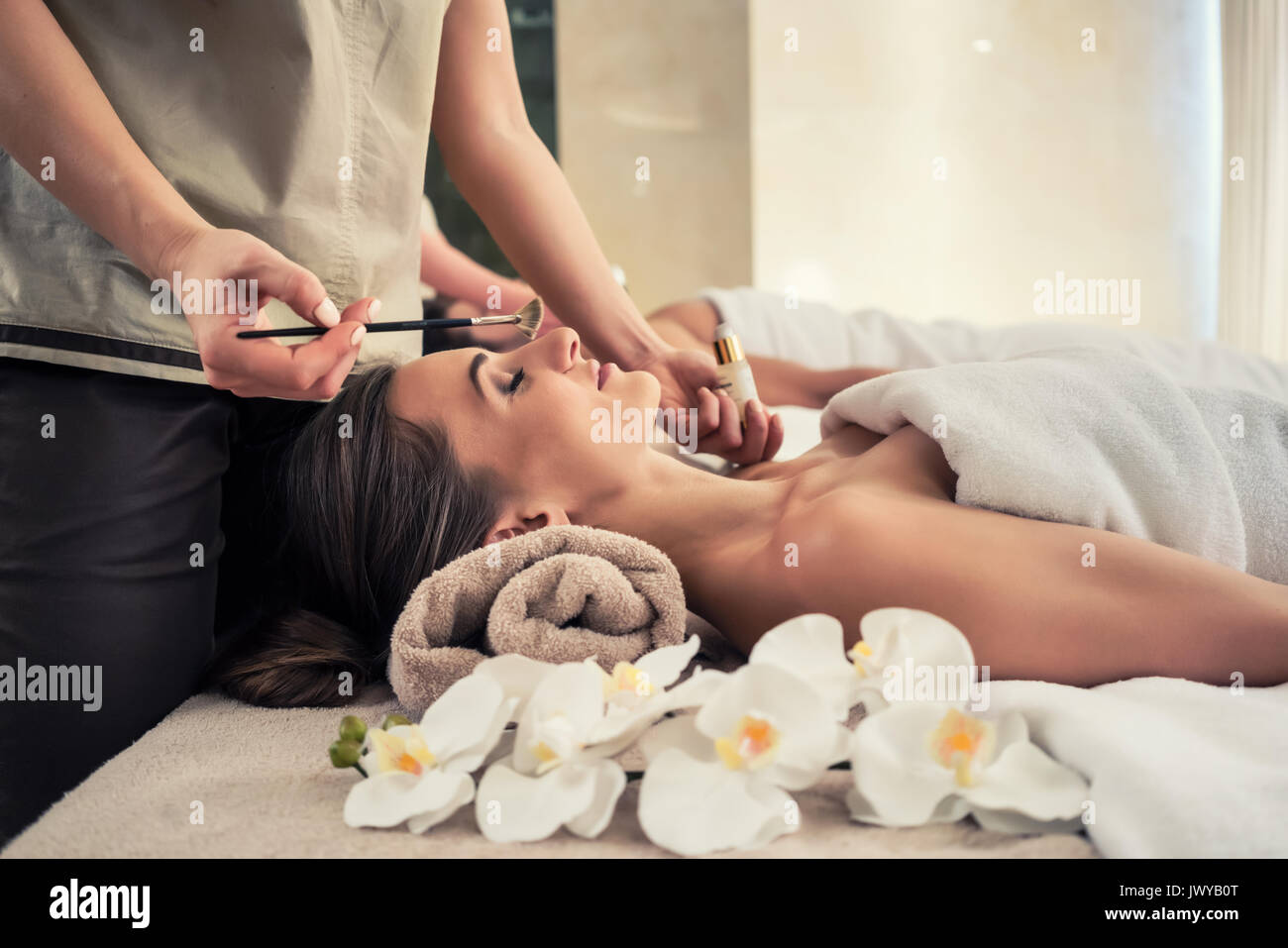 Femme couchée détendue sur lit de massage au cours de traitement du visage Banque D'Images