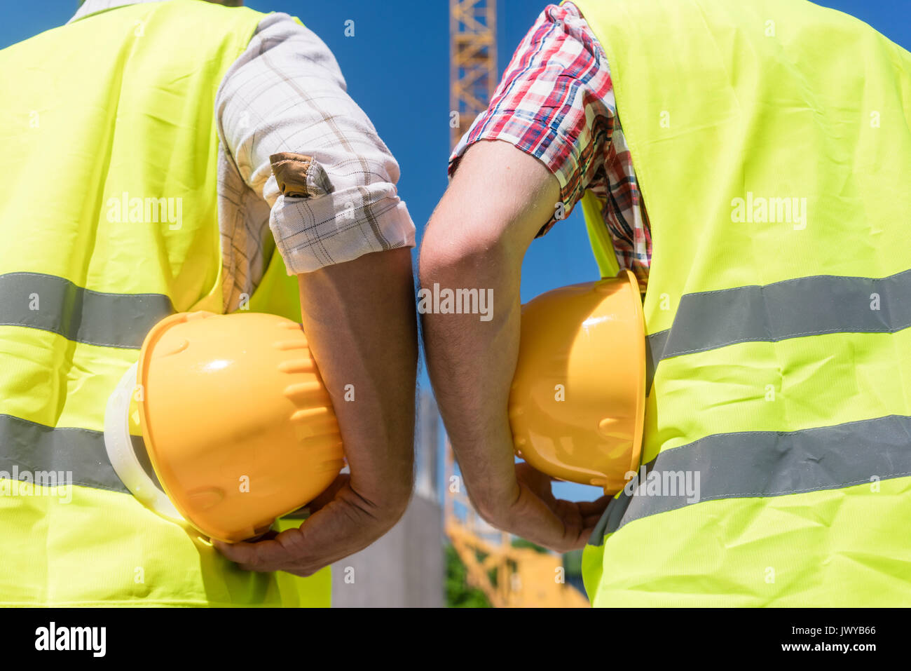 Vue arrière des mains de travailleurs en possession d'un casque jaune de travailleurs de la construction Banque D'Images