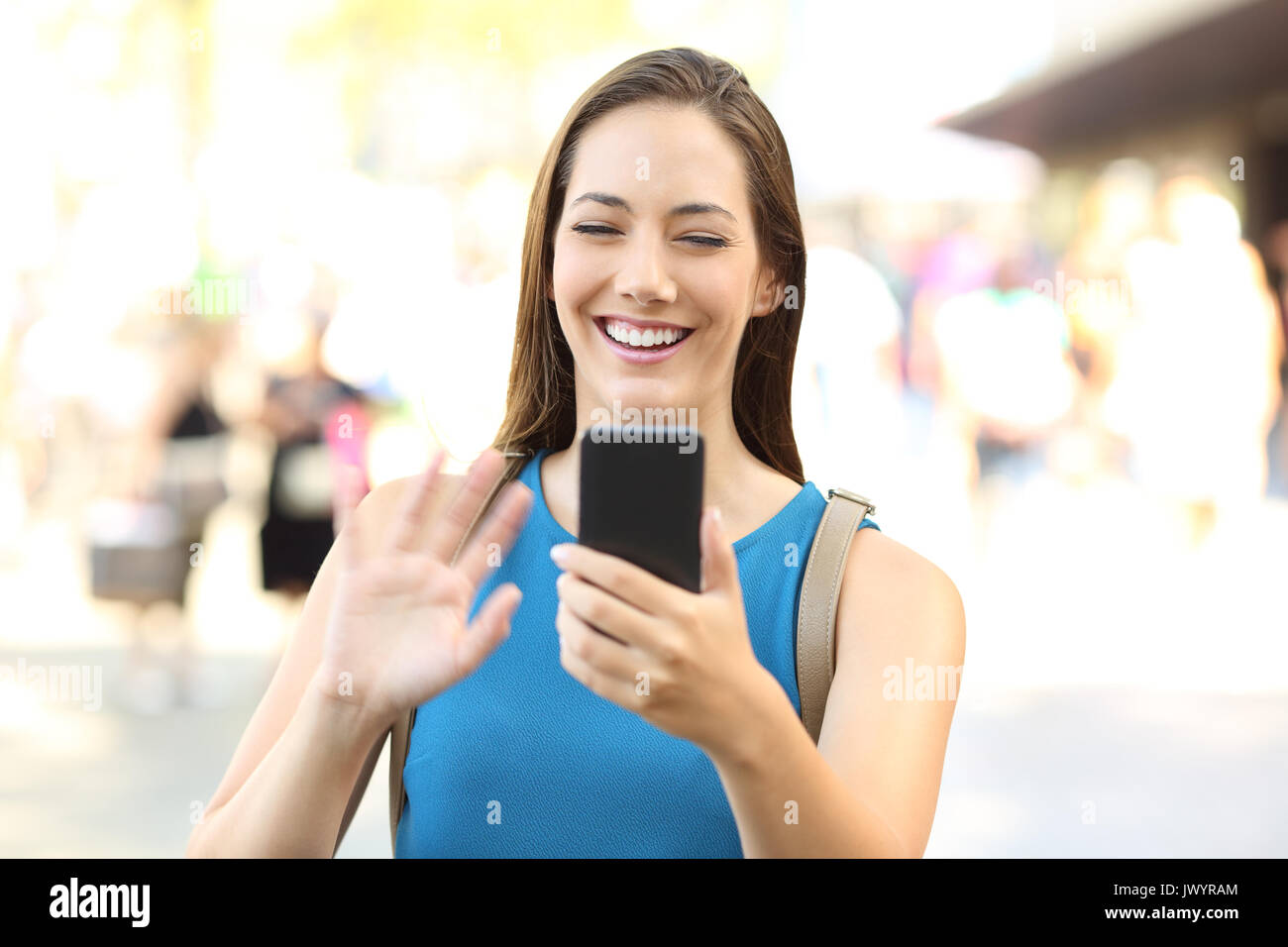 Heureux dame greeting pendant un appel vidéo avec un téléphone intelligent dans la rue Banque D'Images