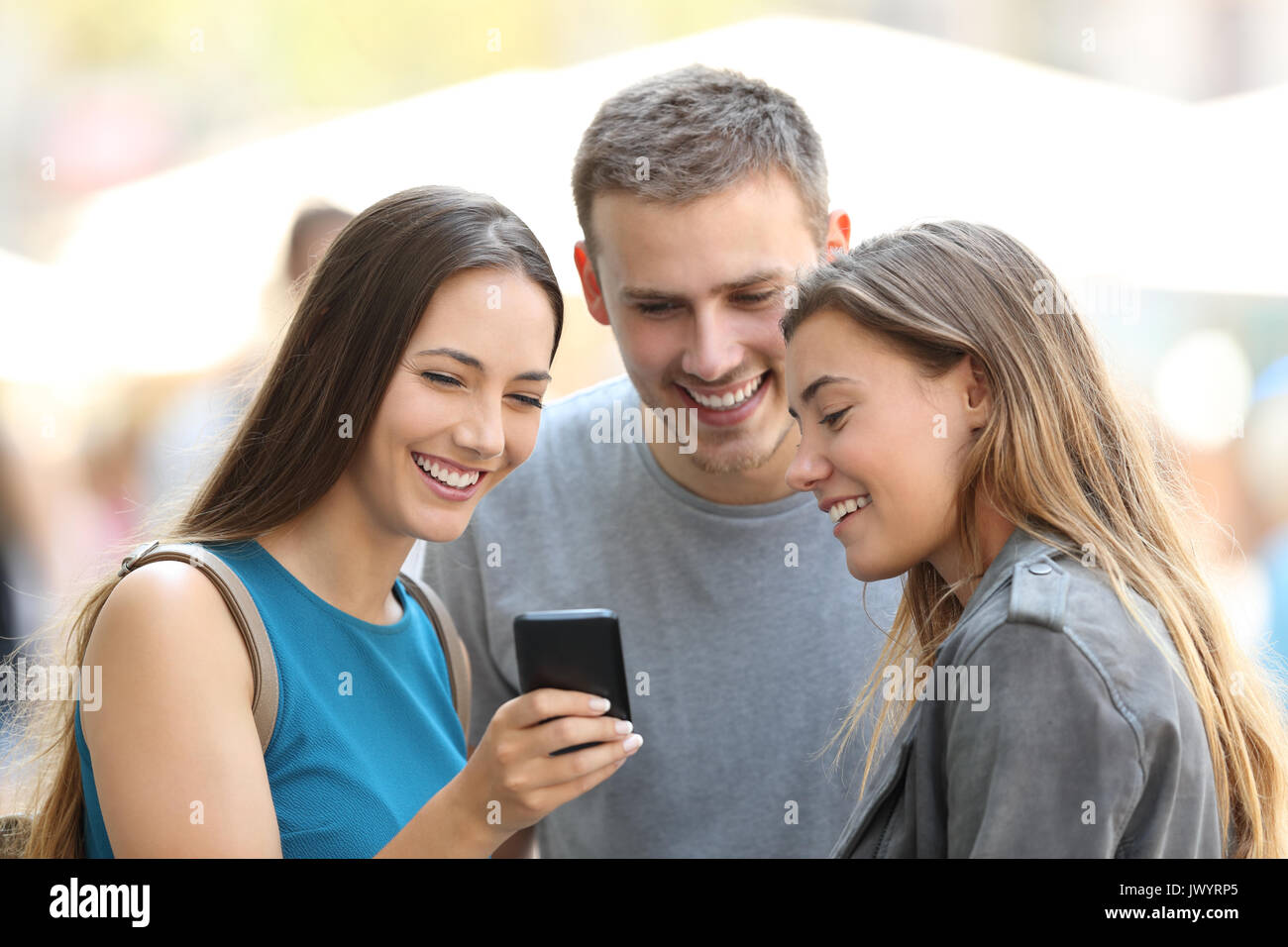 Trois amis heureux smart phone partage du contenu sur la rue Banque D'Images