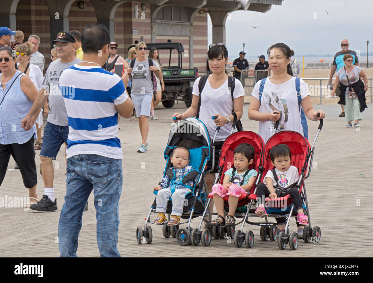 Une famille asiatique en prenant des photos de leur téléphone cellulaire très mignons enfants sur la promenade à Consy Island, Brooklyn, New York. Banque D'Images