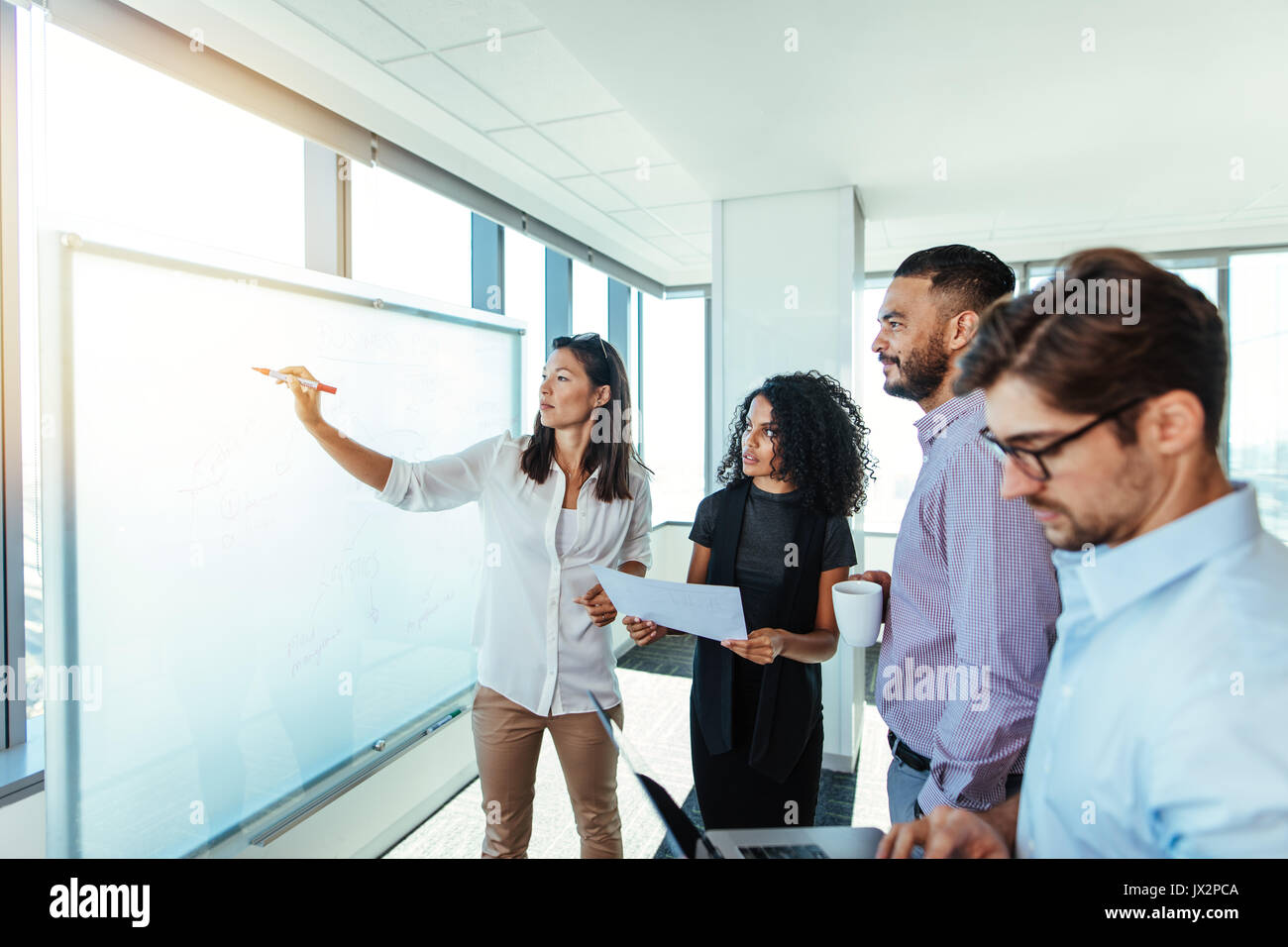 femme d'affaires faisant une présentation sur un tableau blanc à ses collègues. Groupe d'associés d'affaires faisant des plans dans la salle de réunion. Banque D'Images