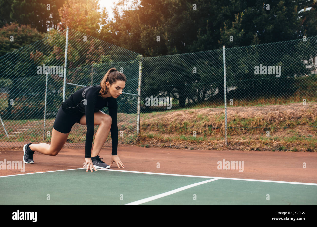 Portrait d'une athlète qui s'étend à l'extérieur. Belle femme exerçant sur un court de tennis. Banque D'Images