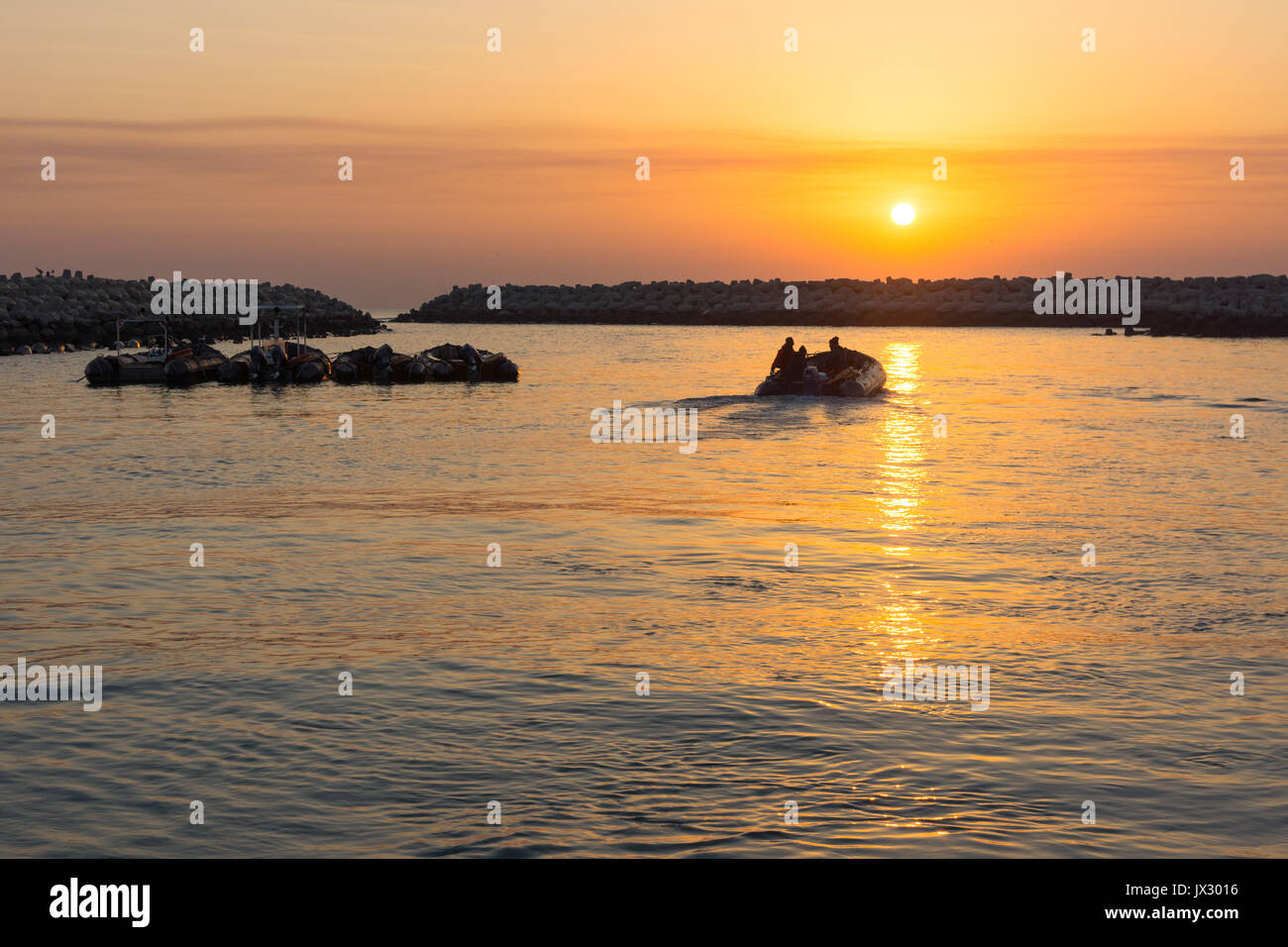 Bateau gonflable zodiac en caoutchouc de quitter un port au lever du soleil dans le Moyen-Orient. Banque D'Images