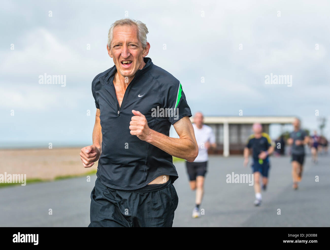 Un homme âgé s'exécutant sur la vitalité de l'événement hebdomadaire Parkrun à Worthing, West Sussex, Angleterre, Royaume-Uni. Banque D'Images