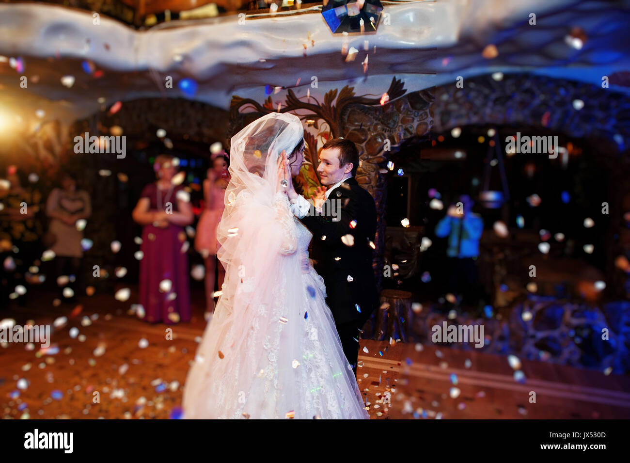 Wedding couple dancing leur première danse dans le restaurant de confettis sur le sol. Banque D'Images