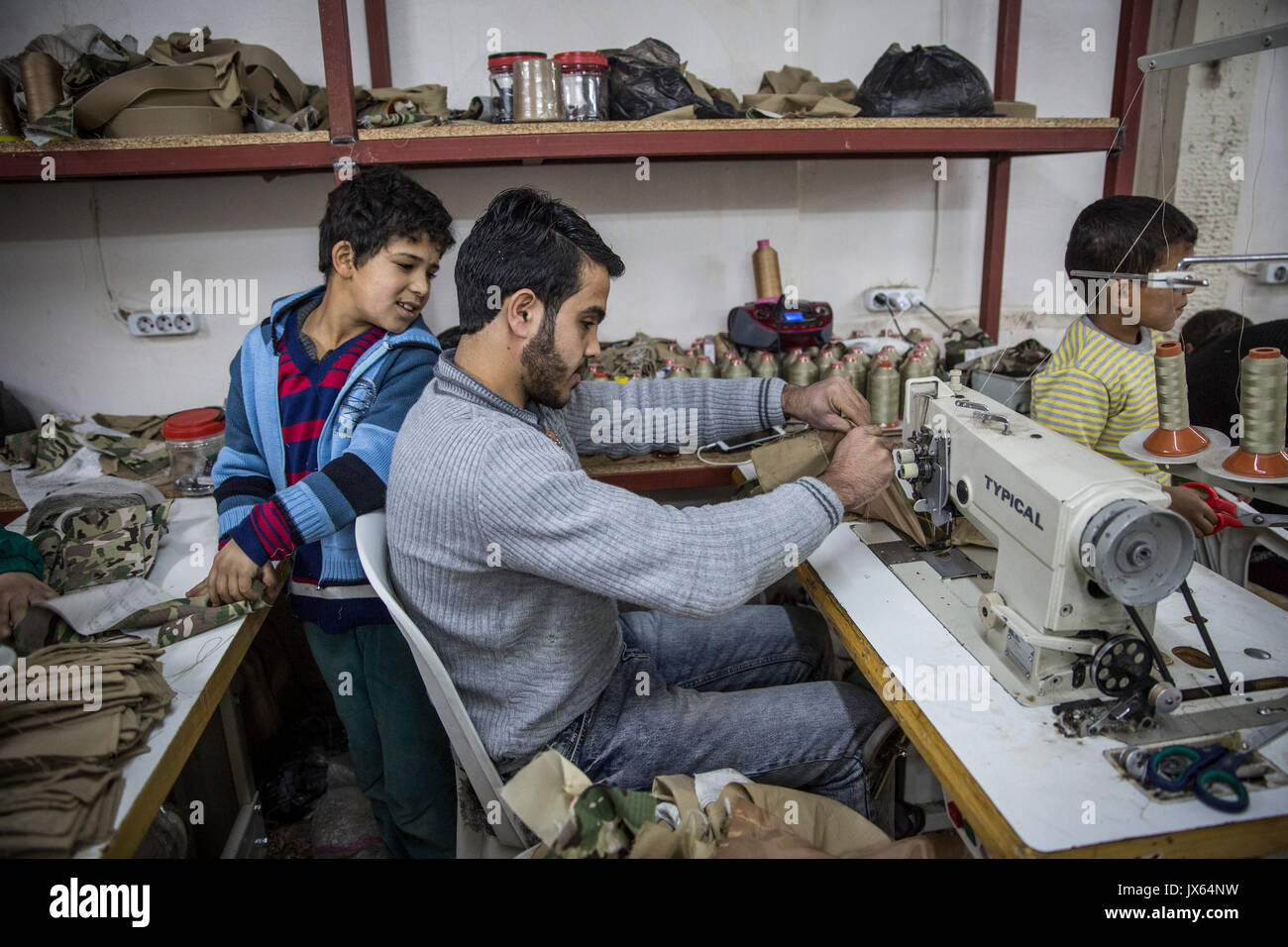 Certains des innombrables nombre d'enfants syriens réfugiés travaillant dans des usines à travers la Turquie, maintenant plus de 2,7 millions de Syriens. La petite boutique textile où lui et d'autres garçons, filles et les hommes sont employés produit des uniformes militaires et des sacs à dos qui sont vendues aux différentes factions en Syrie. La pauvreté conduit de nombreuses familles à envoyer leurs enfants au travail au lieu de à l'école. Les possibilités d'éducation pour les Syriens en Turquie sont également limitées. Banque D'Images