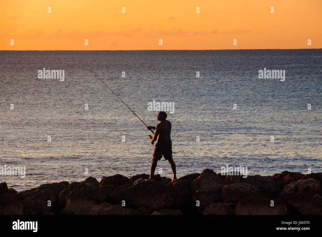 Un homme casting plage au coucher du soleil à la Barbade, Caraïbes Isles Banque D'Images