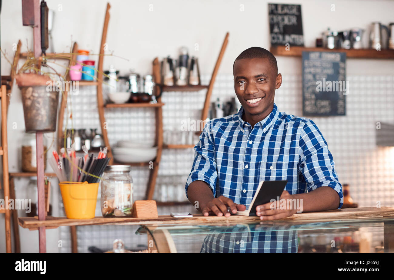 Souriante jeune entrepreneur africain travaillant dans son cafe Banque D'Images