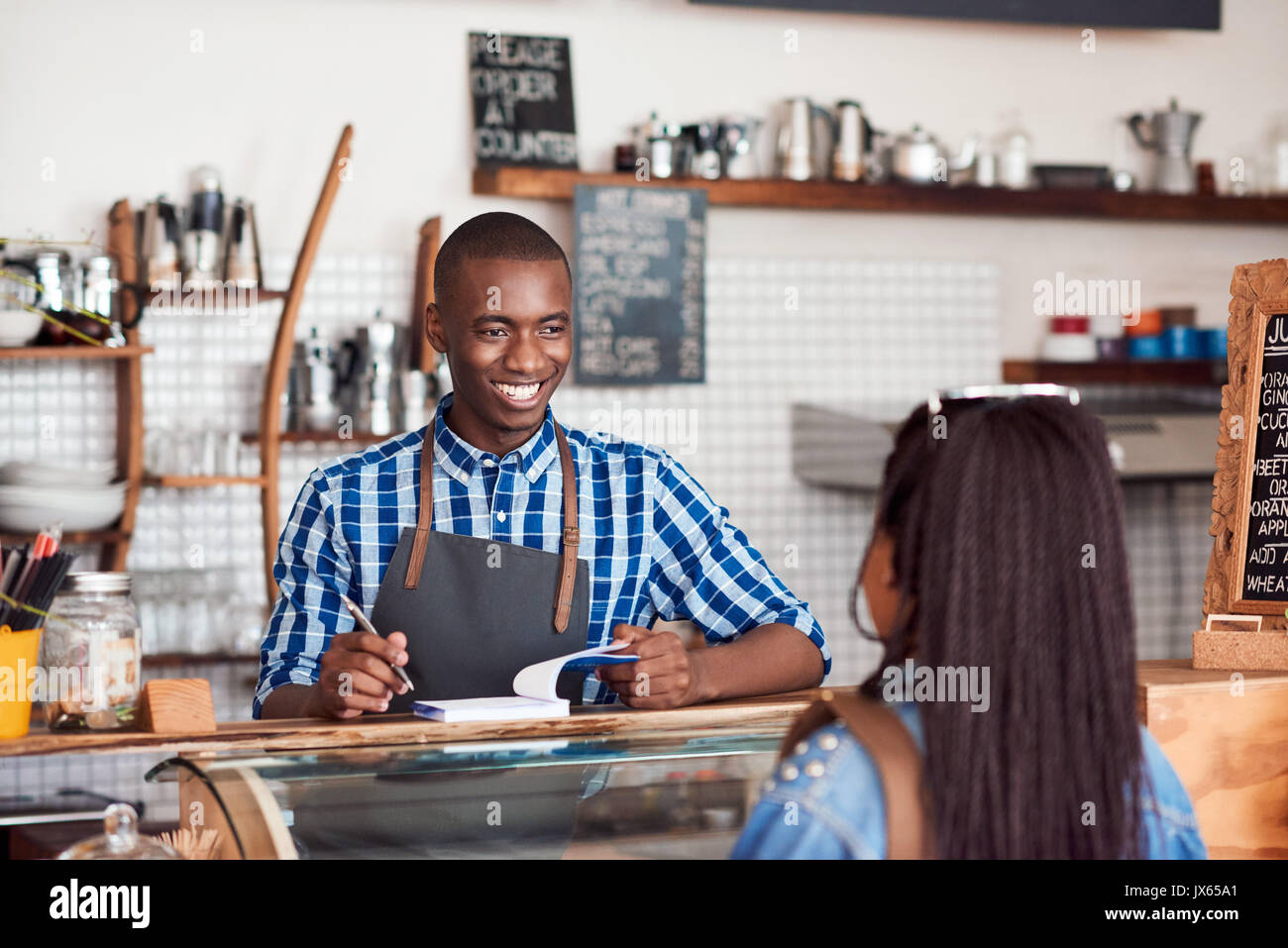 Smiling barista de parler à un client dans son cafe Banque D'Images