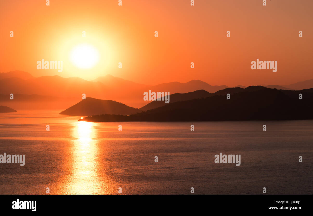 Lever du soleil sur la baie en Turquie avec calme la lumière et encore de l'eau. Montagnes à l'horizon Banque D'Images