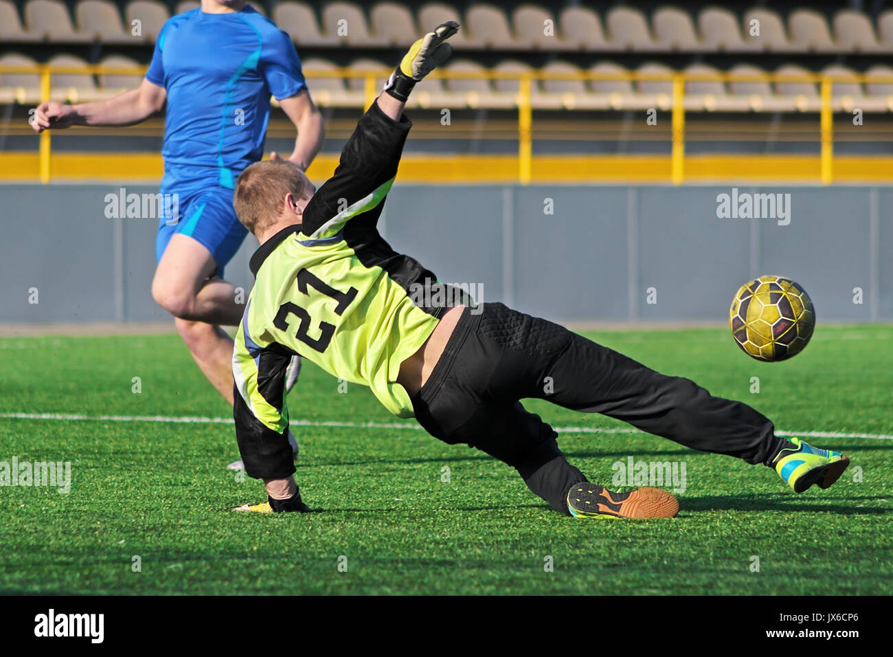 Gardien de la localisation d'attraper balle. Joueur de football et aller de l'attaquant sur le terrain de stade. Gardien attrape la balle. Joueur de football et Banque D'Images