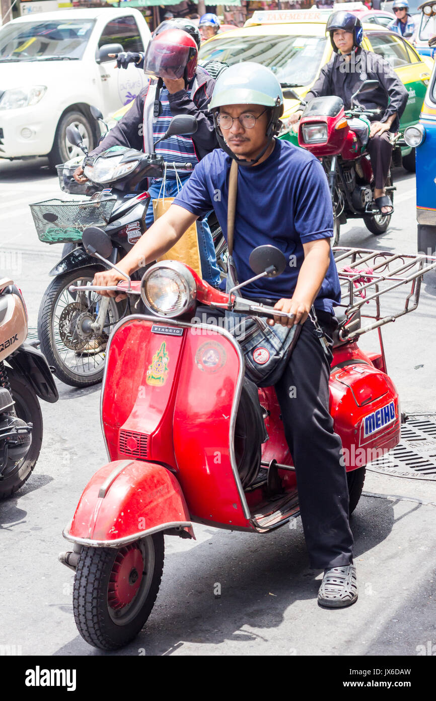 Piaggio scooter rouge sur l'homme en attente de feux de circulation pour changer de Chinatown, Bangkok, Thaïlande Banque D'Images