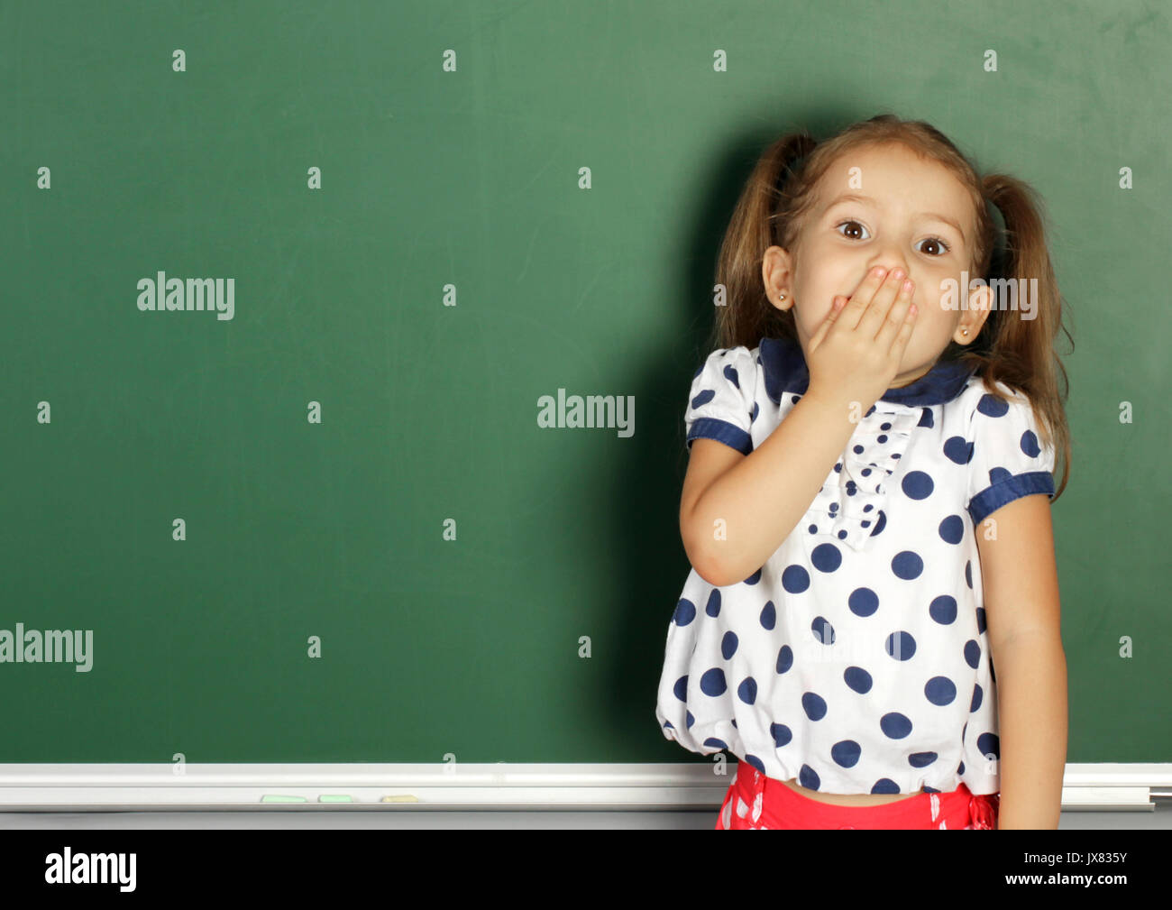 Enfant souriant près de l'école vide tableau noir, copy space Banque D'Images