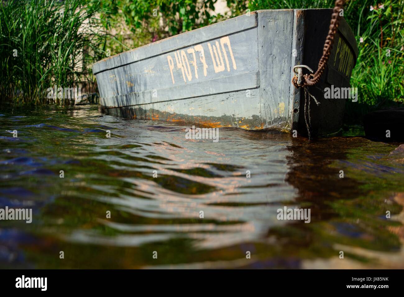 Le bateau de pêcheurs est liée d'une épaisse chaîne sur le rivage d'un lac propre Banque D'Images