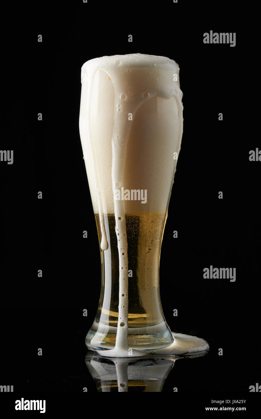 Mousse de la bière venant de verre isolé sur fond noir Banque D'Images