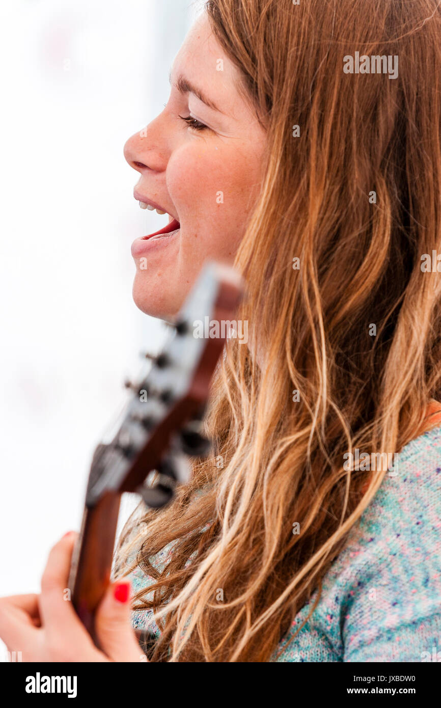 L'Angleterre, Ramsgate. Gator, bande chien Snappers, jeune femme avec les cheveux bruns guitariste et chanteur qui joue de la guitare et chanter. Close-up. Banque D'Images